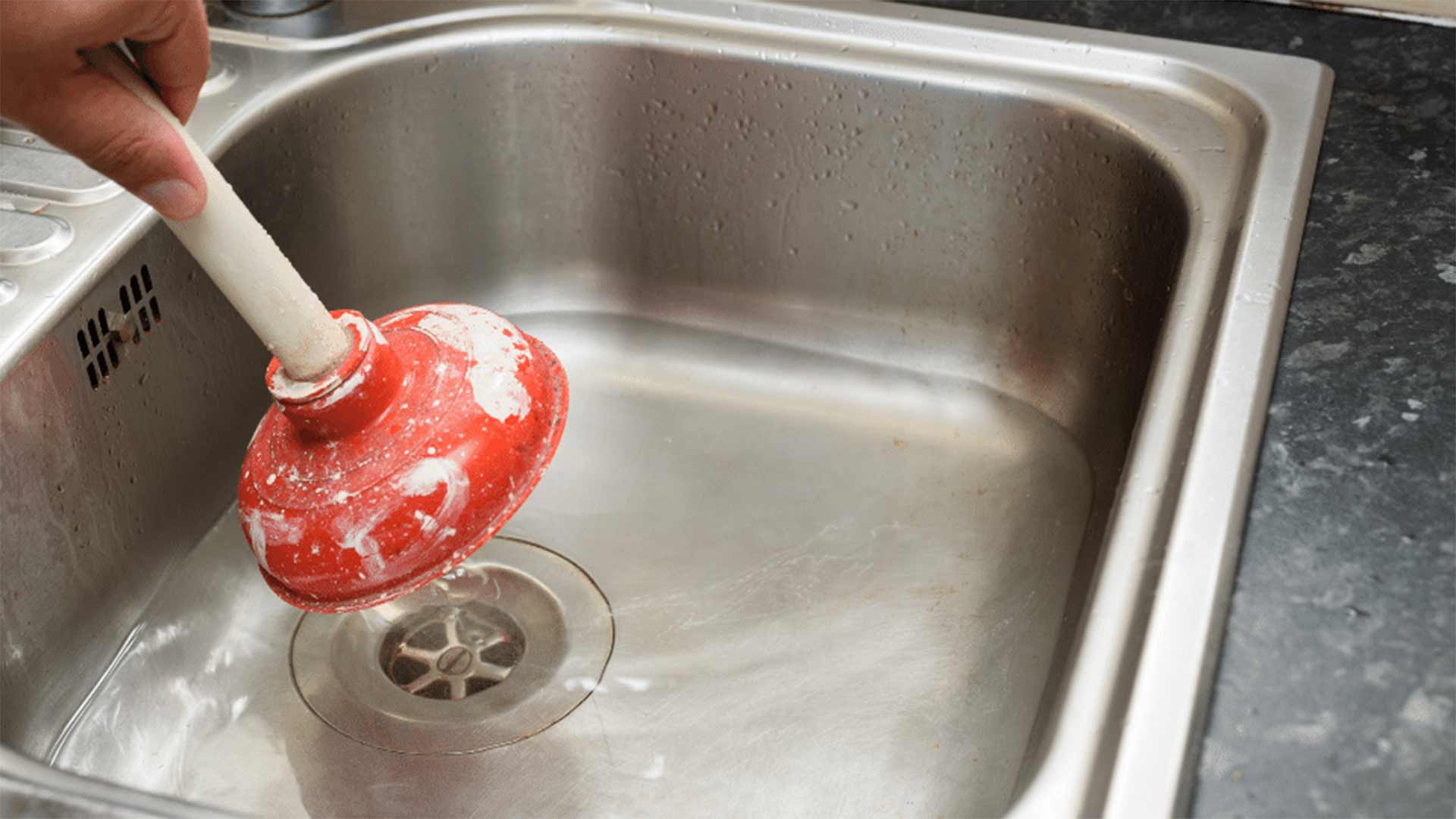 Water pooling in a clogged kitchen sink that needs professional drain cleaning.