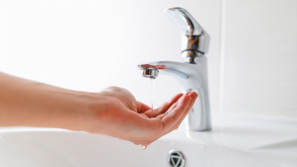 A hand catching a few droplets of faucet water.