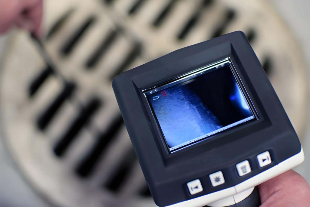 Sewer camera inspection cost: technician viewing live sewer pipe footage on a camera monitor