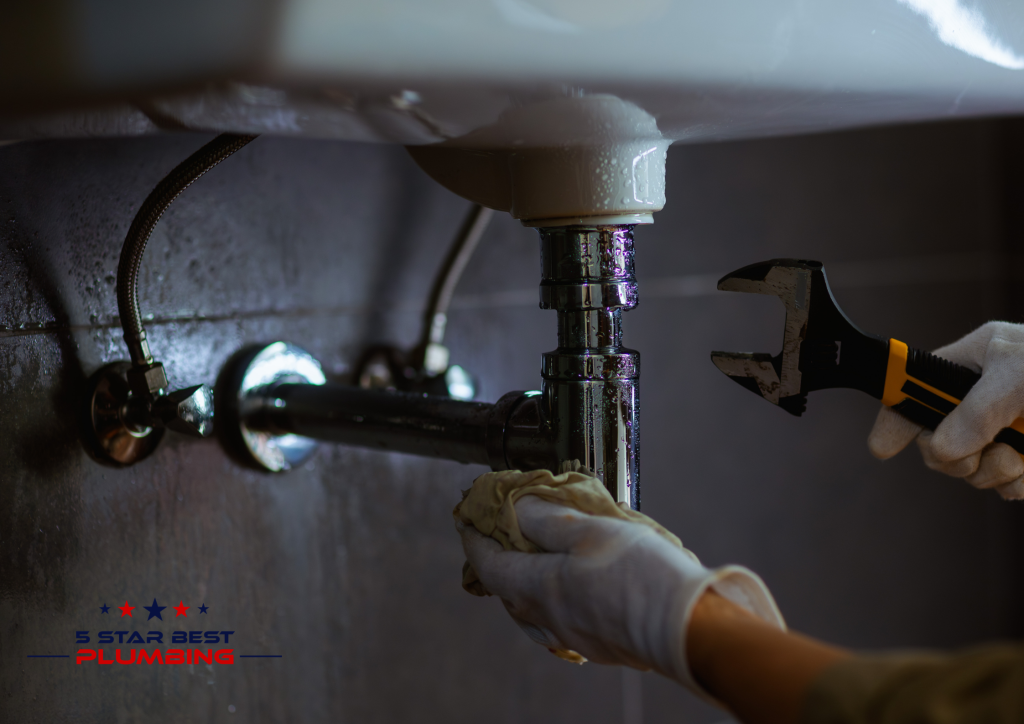 5 Star Best Plumbing licensed plumber repairing pipes under a sink with a wrench and professional gloves