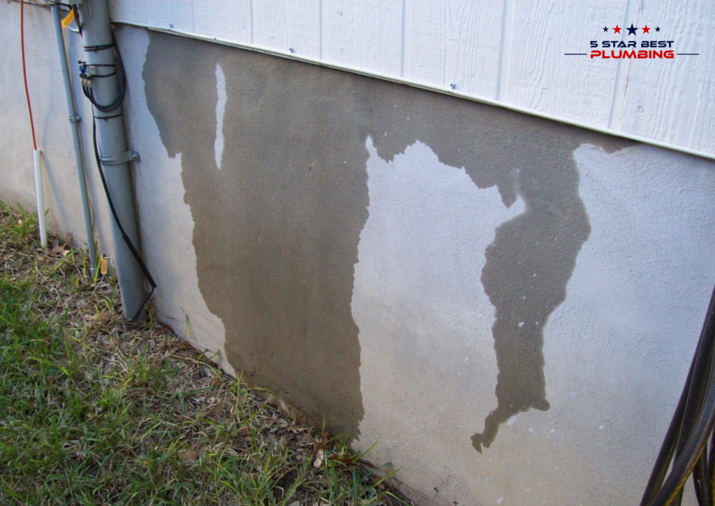 Water stains streaking down exterior home foundation wall indicating a hidden pipe leak or slab leak underneath